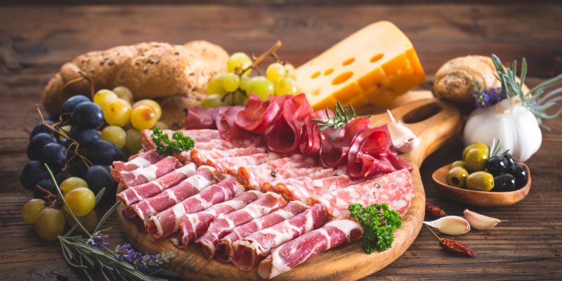 Cutting board with prosciutto, salami, ham, cheese, bread and olives